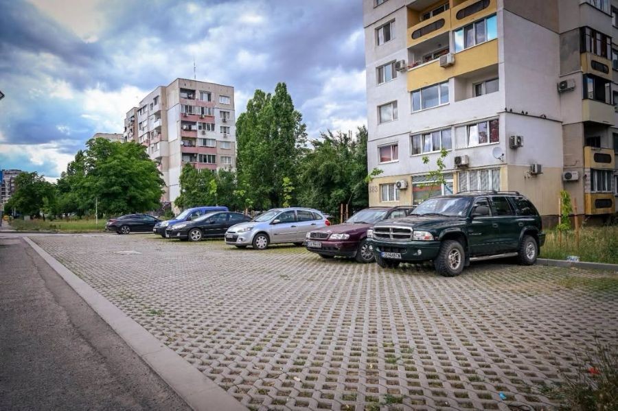 Облагородено междублоково пространство в софийски квартал с новоизграден зелен паркинг с решетъчни бетонови елементи и паркирани автомобили. 