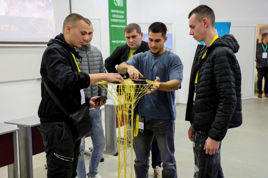Ученици от ПГСАГ тестват здравината и носимоспособността на изградена конструкция от спагети по време на състезанието във ВСУ. 